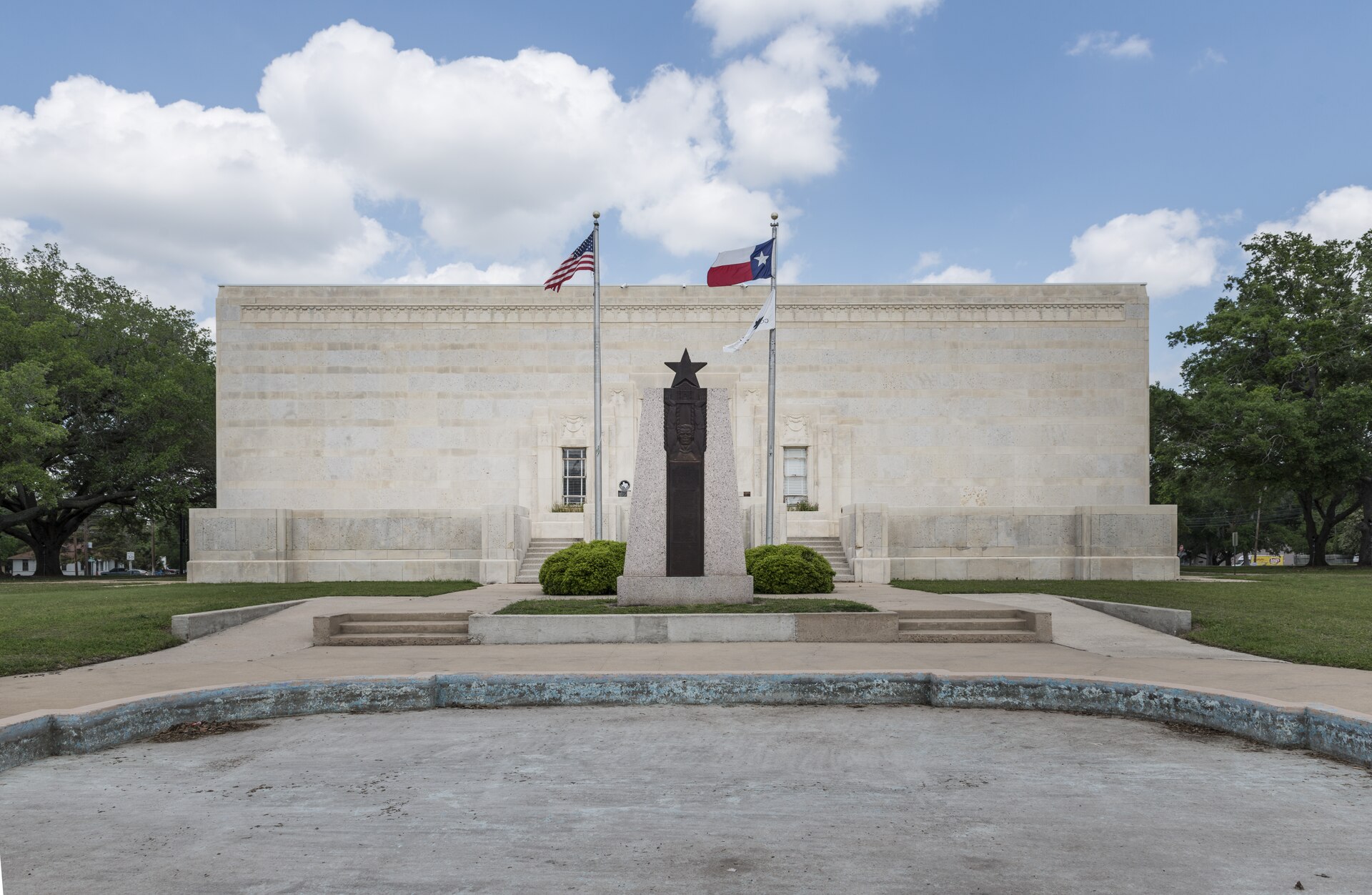 The limestone Gonzales Memorial Museum with Texas and U.S. flags